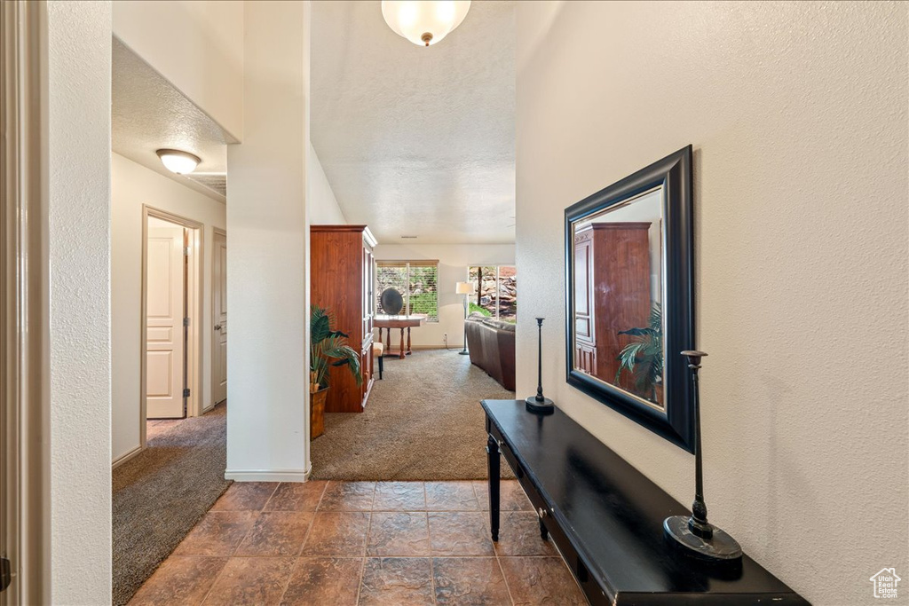 Hallway featuring carpet floors, baseboards, and stone finish floors