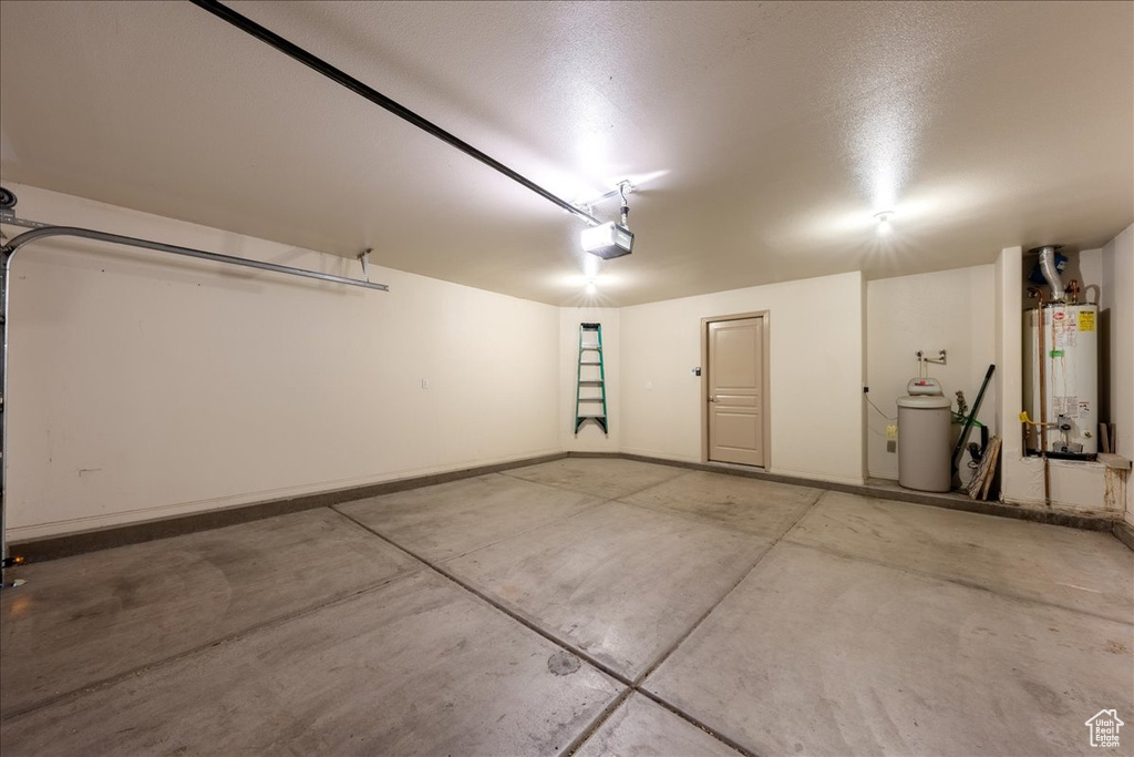 Garage featuring water heater, a garage door opener, and baseboards