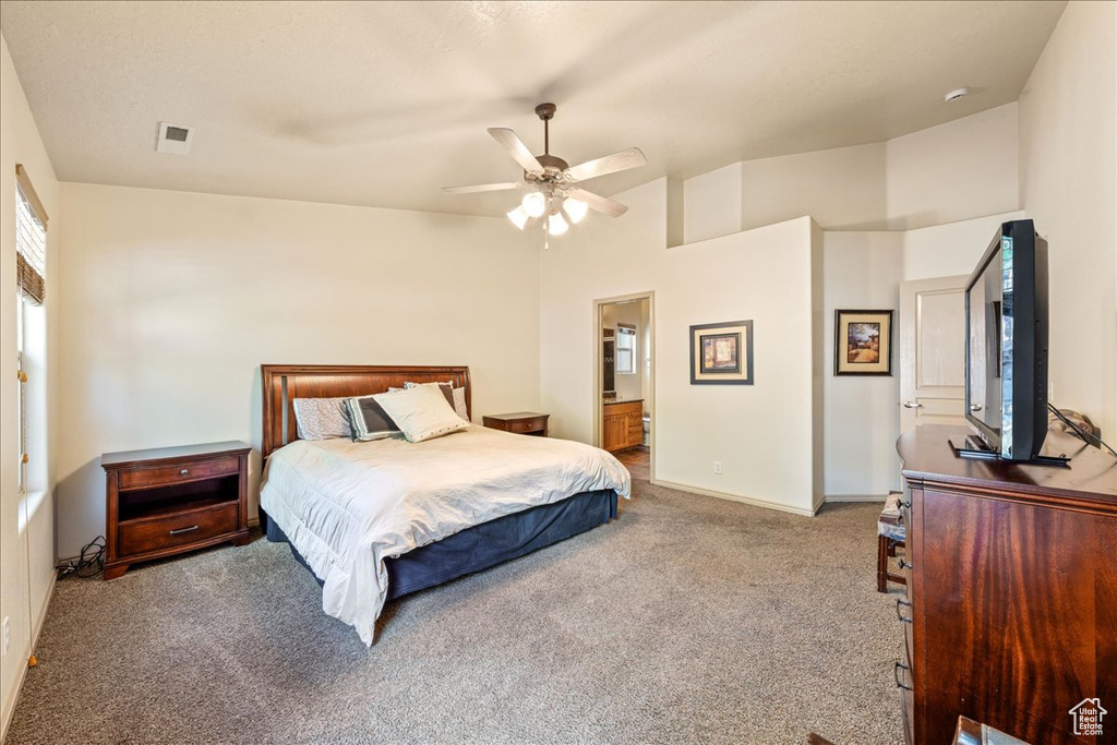 Carpeted bedroom featuring baseboards, ceiling fan, and ensuite bathroom
