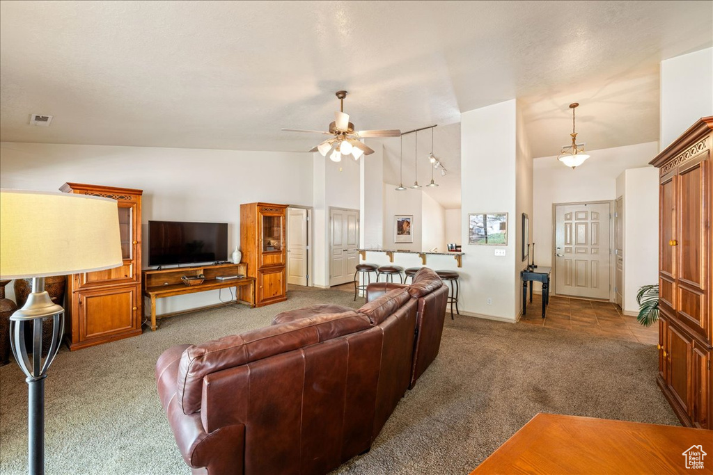 Living area with carpet floors, high vaulted ceiling, a ceiling fan, and baseboards