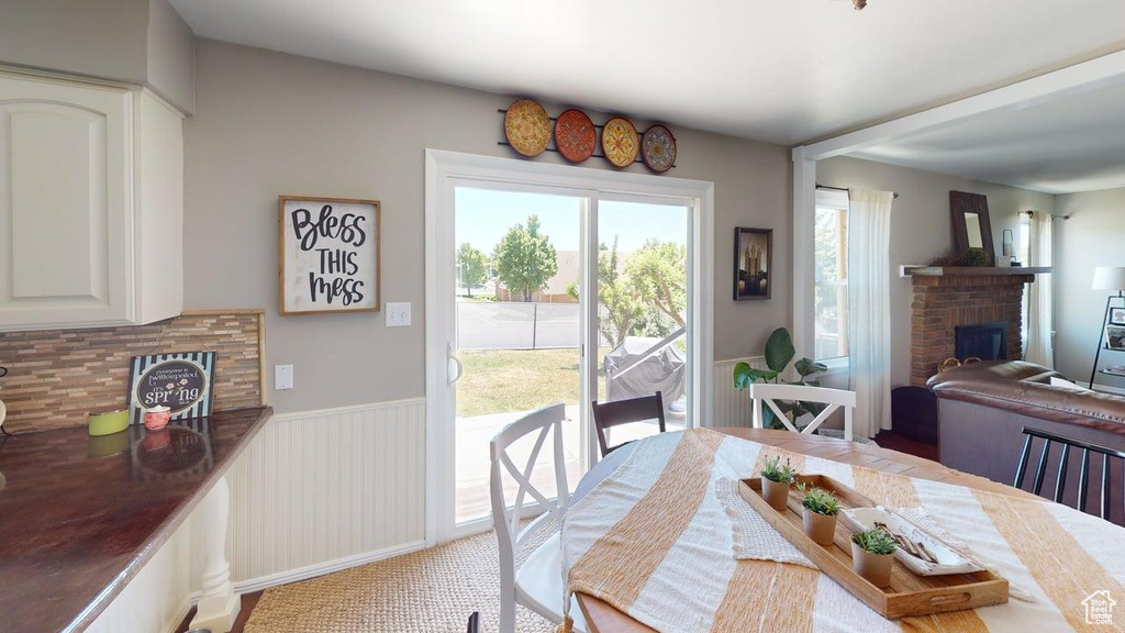 Dining area featuring a fireplace, wainscoting, and light carpet