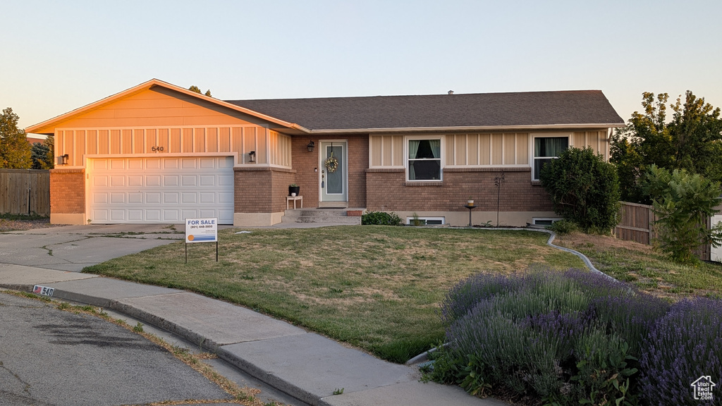 Single story home featuring a garage, driveway, board and batten siding, and brick siding