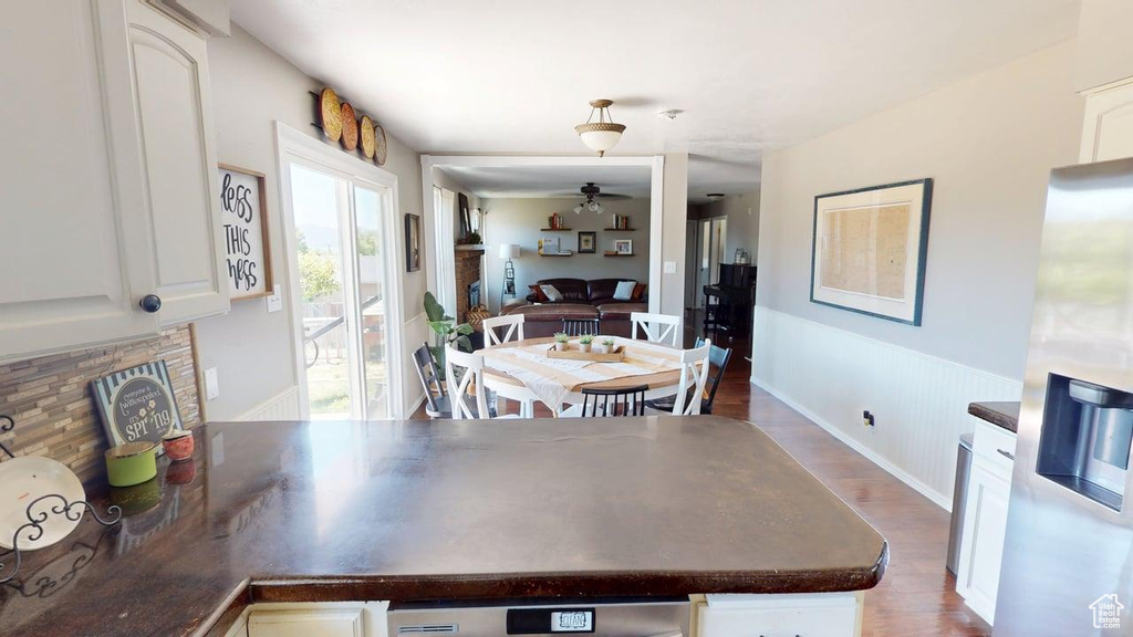 Dining area featuring a ceiling fan, wood finished floors, and a wainscoted wall