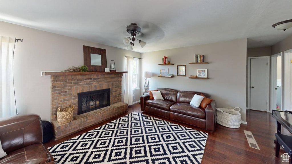 Living area featuring ceiling fan, wood finished floors, a brick fireplace, and baseboards