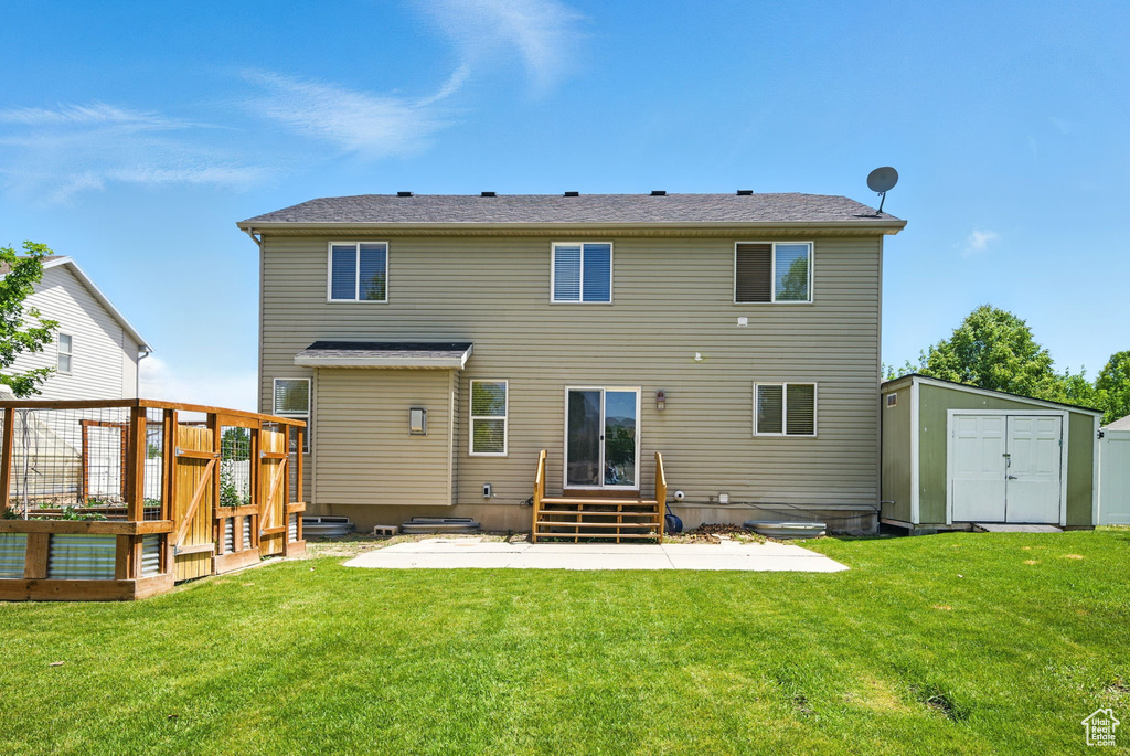 Back of house featuring a wooden deck, a patio, and a yard