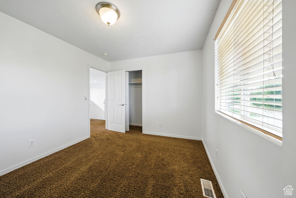 Unfurnished bedroom with carpet floors, a closet, and baseboards