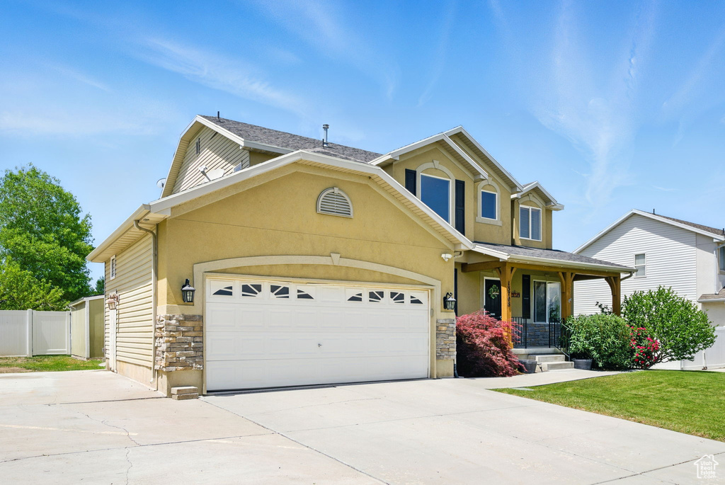 Traditional-style home featuring stone siding, concrete driveway, a garage, a porch, and stucco siding