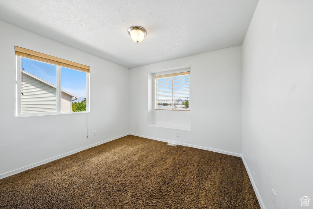 Unfurnished room with dark colored carpet and baseboards