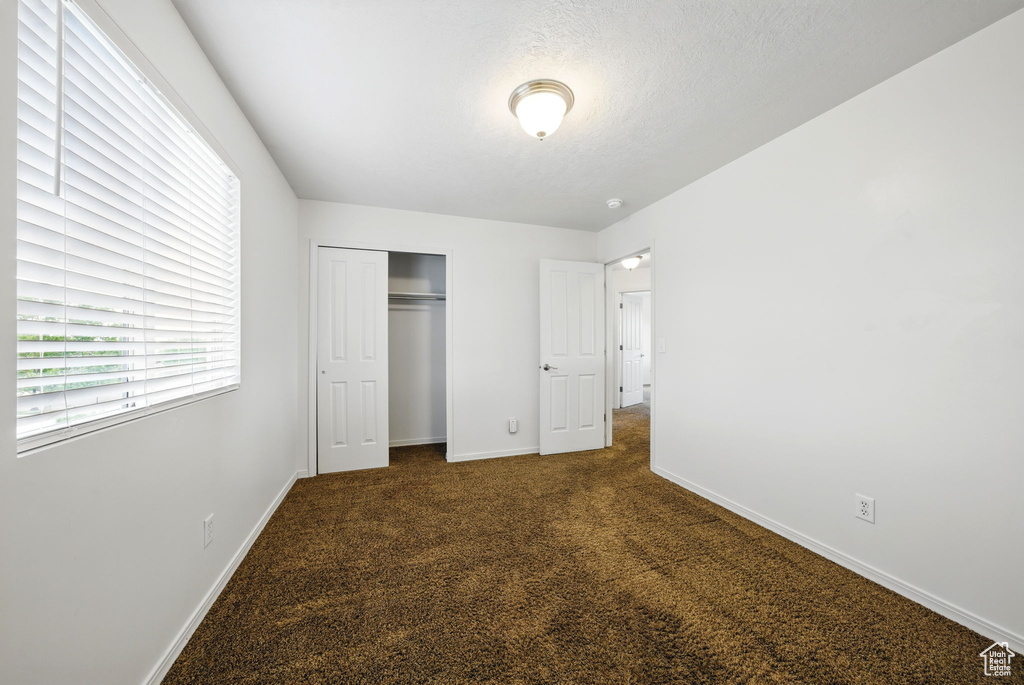 Unfurnished bedroom with carpet flooring, a closet, and baseboards