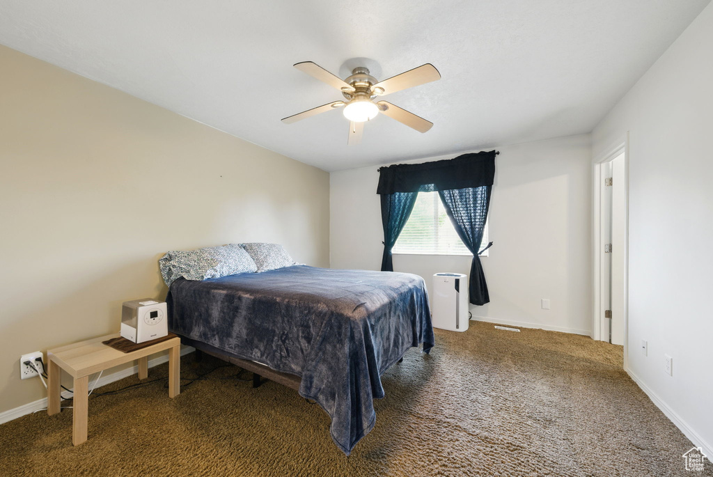 Carpeted bedroom featuring ceiling fan and baseboards