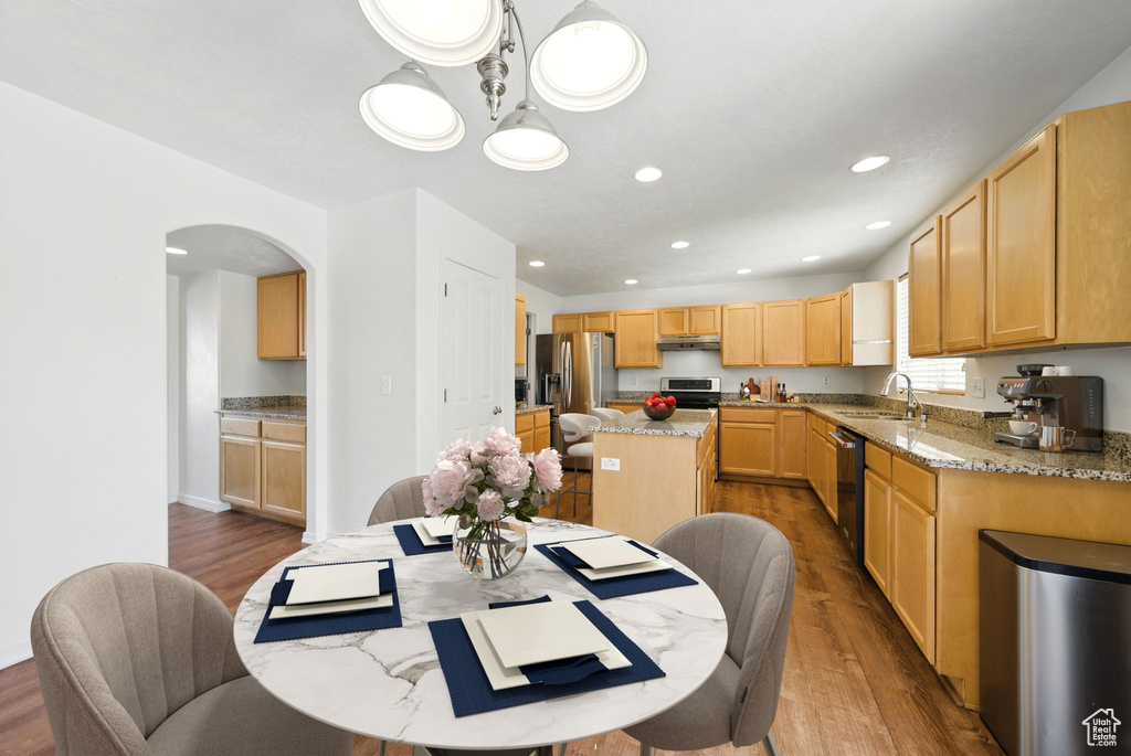 Dining space featuring wood finished floors, arched walkways, recessed lighting, and baseboards