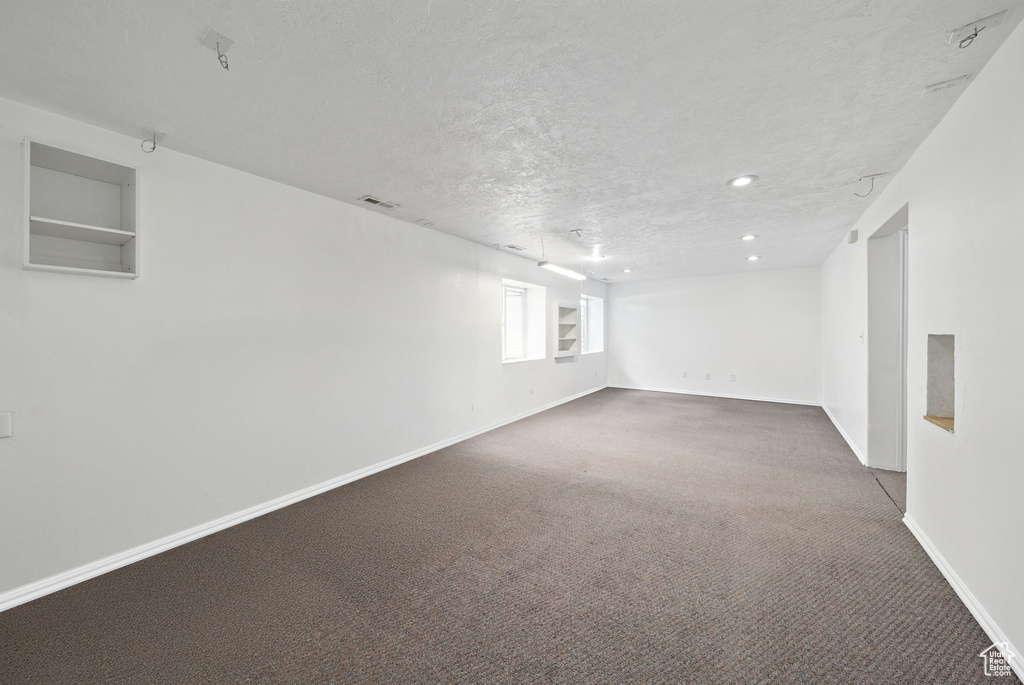 Below grade area featuring carpet floors, a textured ceiling, baseboards, and recessed lighting