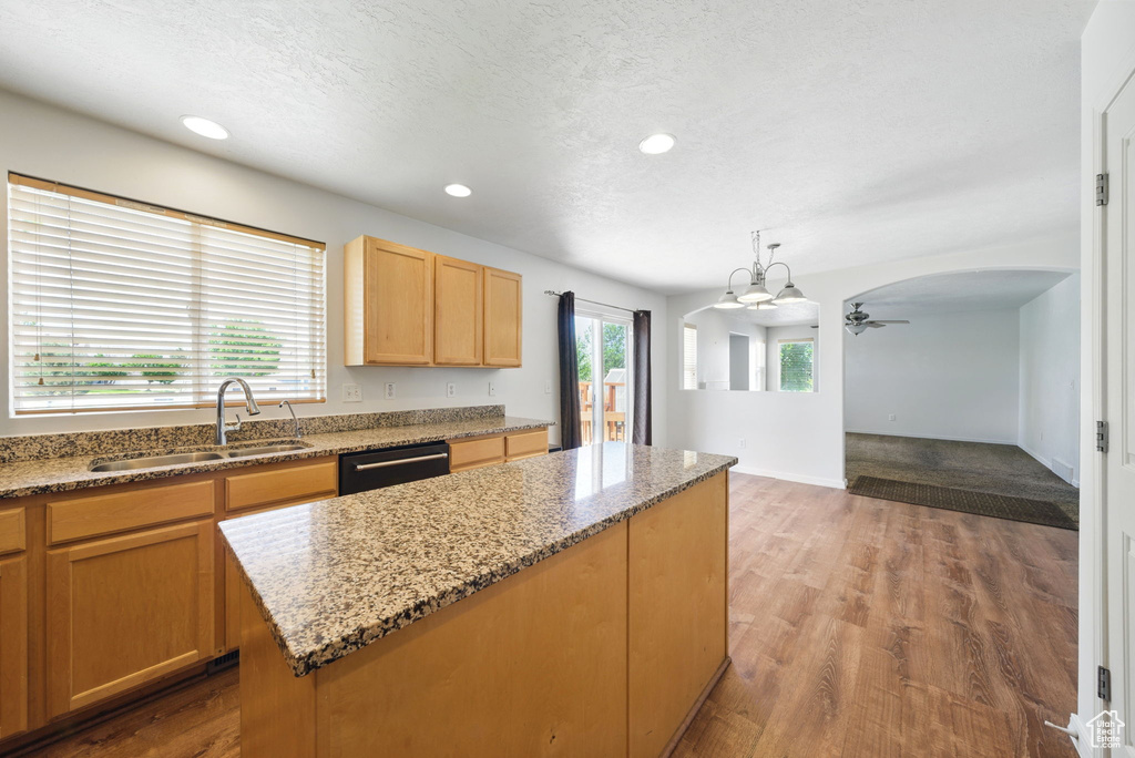 Kitchen with a sink, dishwashing machine, ceiling fan, wood finished floors, and a kitchen island