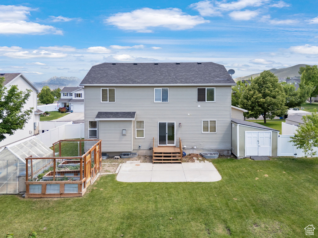 Back of property with a patio area, a garden, a mountain view, and a shingled roof