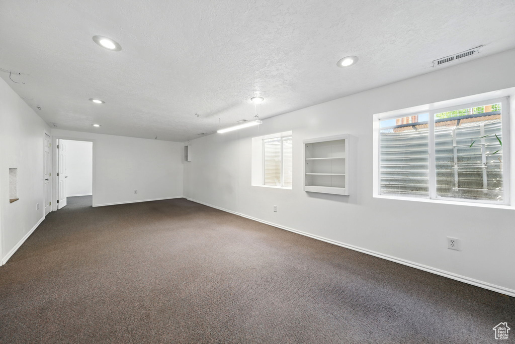 Unfurnished room featuring baseboards, recessed lighting, dark colored carpet, and a textured ceiling