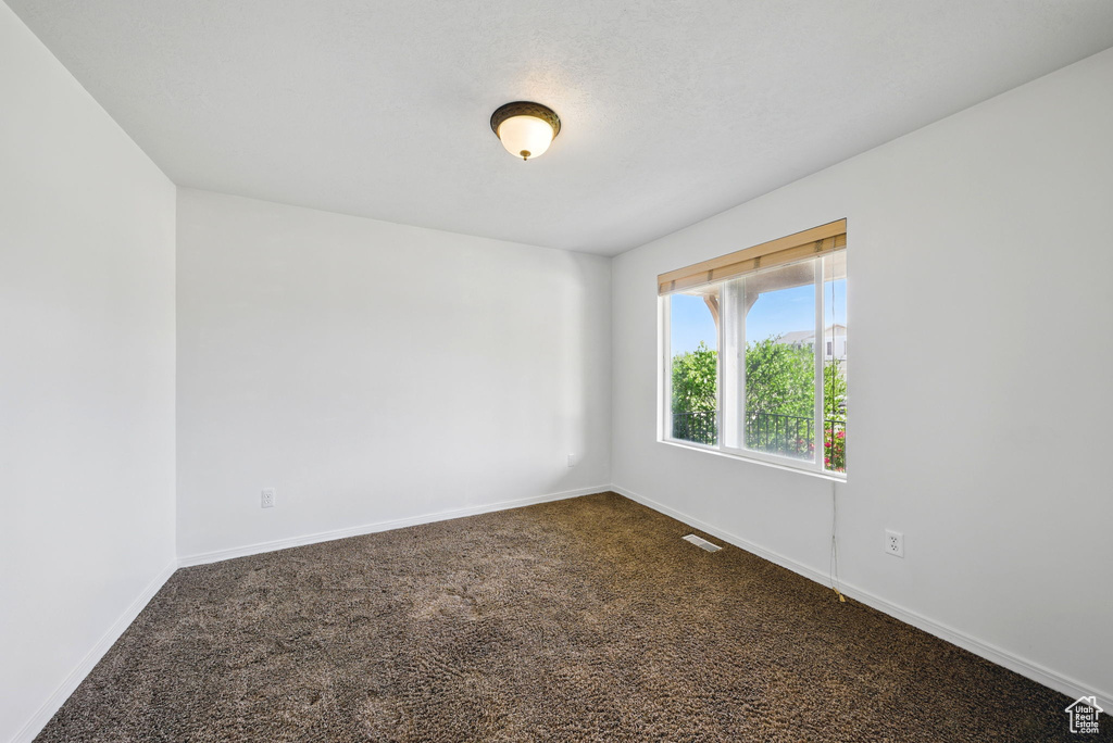 Empty room with dark carpet and baseboards