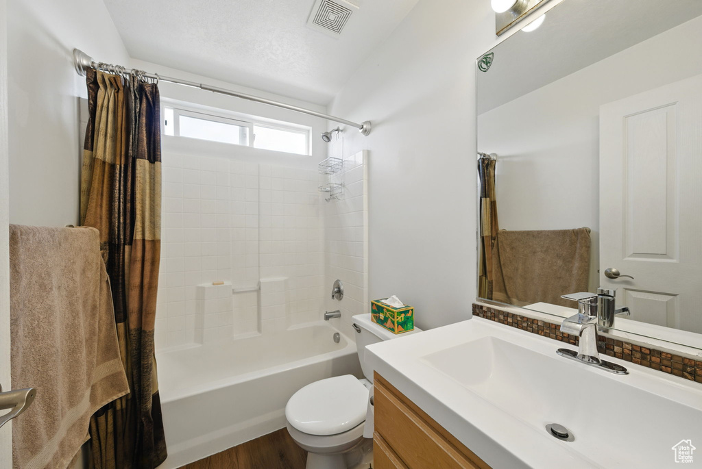 Bathroom featuring shower / tub combo, vanity, toilet, and wood finished floors