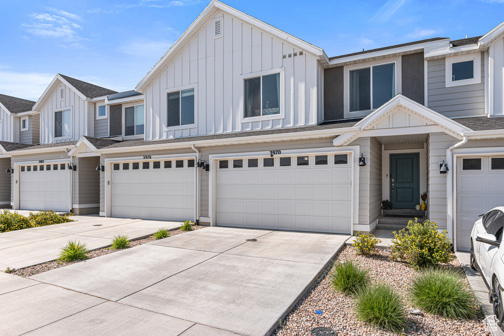 Townhome / multi-family property featuring board and batten siding, an attached garage, and driveway