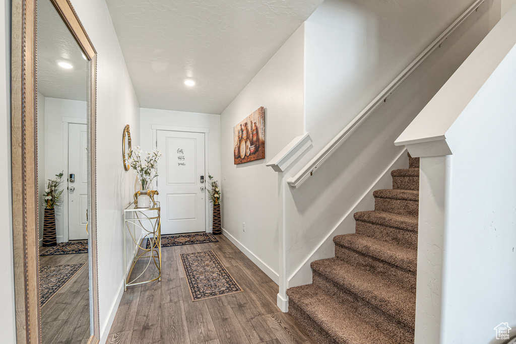 Foyer featuring wood finished floors, baseboards, stairs, and recessed lighting