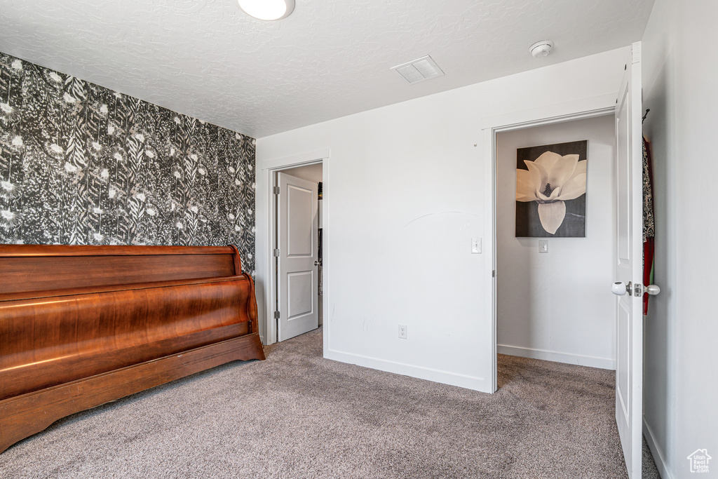 Unfurnished bedroom featuring carpet, baseboards, and a textured ceiling