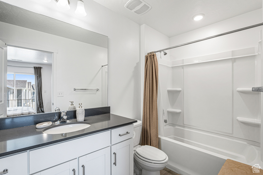 Full bathroom featuring vanity, shower / tub combo with curtain, and toilet