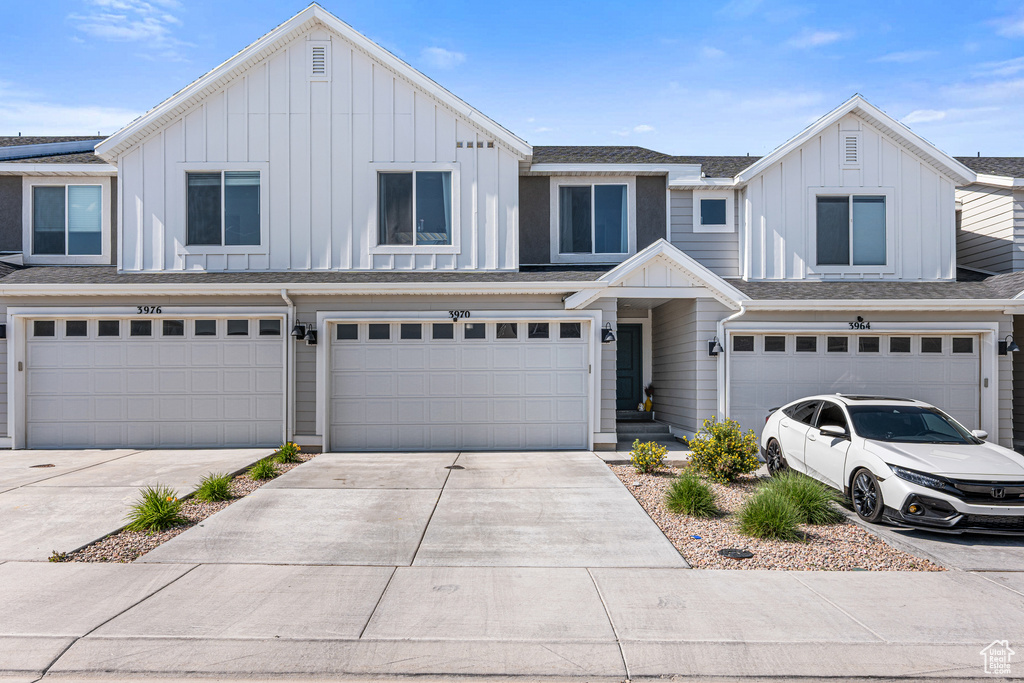 View of property with a garage, board and batten siding, and driveway
