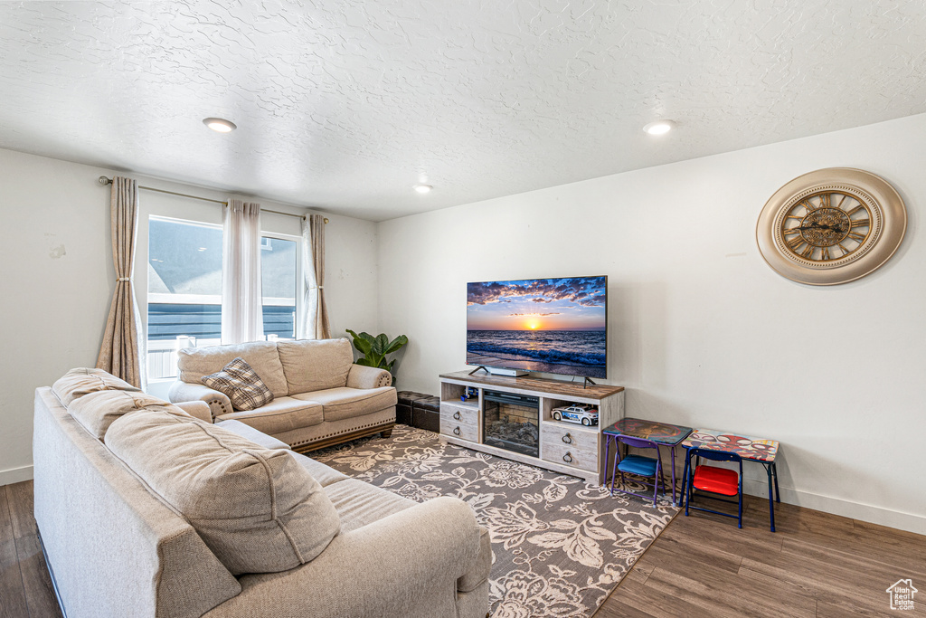 Living area with a textured ceiling, baseboards, wood finished floors, and recessed lighting
