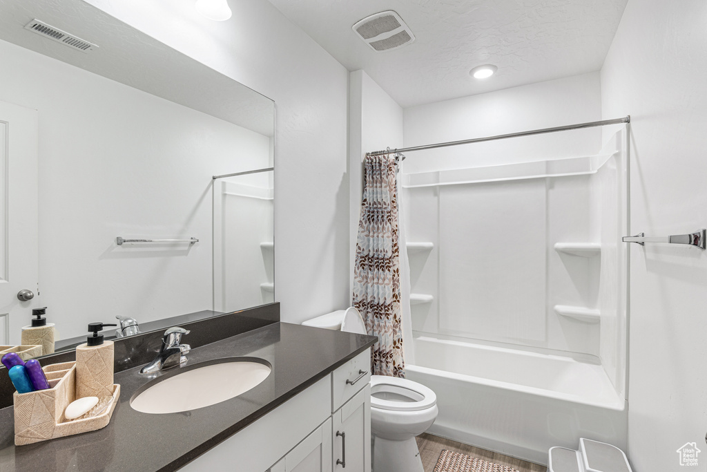 Bathroom featuring toilet, vanity, and shower / bath combo