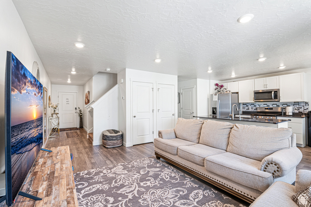 Living room with light wood-type flooring, recessed lighting, baseboards, and a textured ceiling