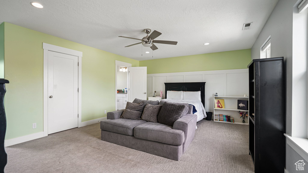 Carpeted bedroom featuring a fireplace, recessed lighting, ceiling fan, ensuite bath, and a textured ceiling