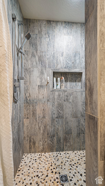 Bathroom featuring tiled shower and a textured ceiling