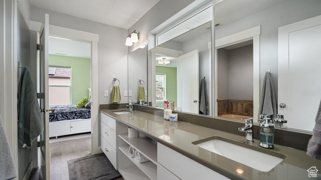 Full bath with healthy amount of natural light, double vanity, and a bath