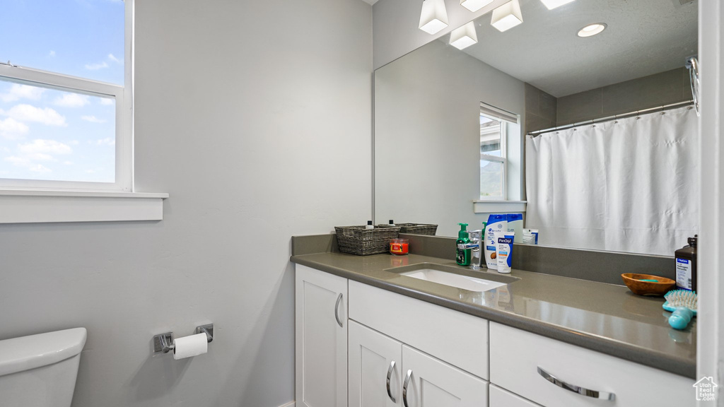 Full bathroom with toilet, vanity, recessed lighting, and a shower with shower curtain