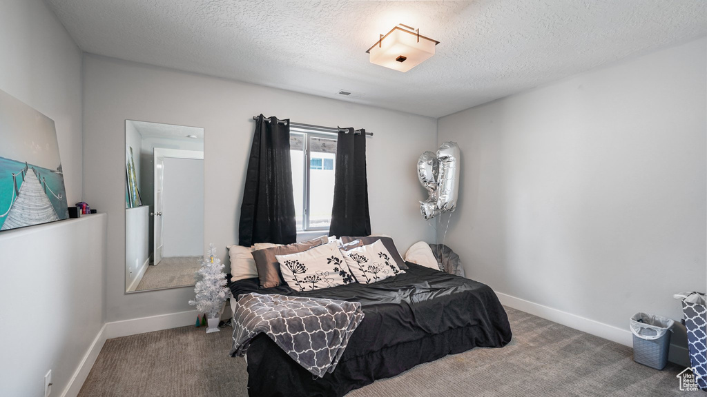 Carpeted bedroom with baseboards and a textured ceiling