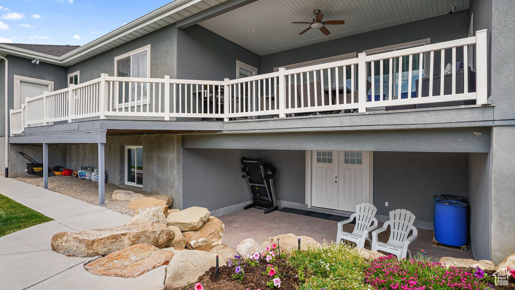 Rear view of property featuring ceiling fan, stucco siding, and a balcony