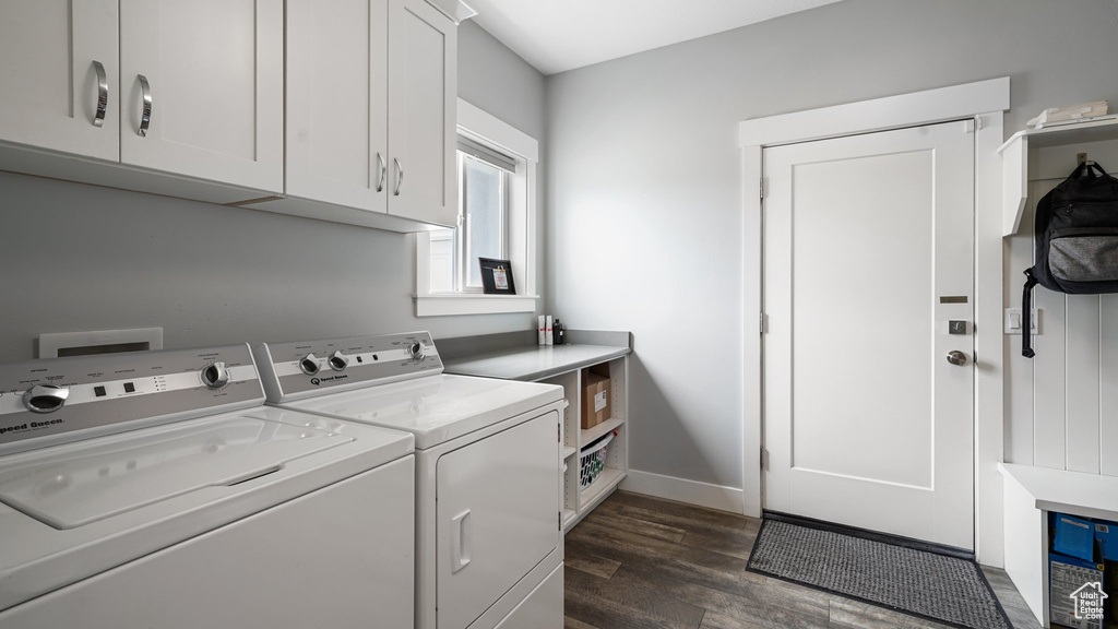 Washroom with cabinet space, washing machine and dryer, dark wood finished floors, and baseboards