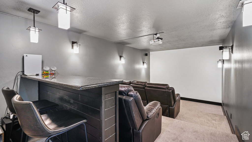 Home theater with light carpet, a textured ceiling, and baseboards