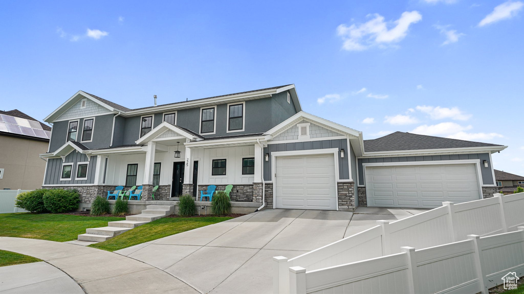View of front facade with board and batten siding, a garage, driveway, and stone siding