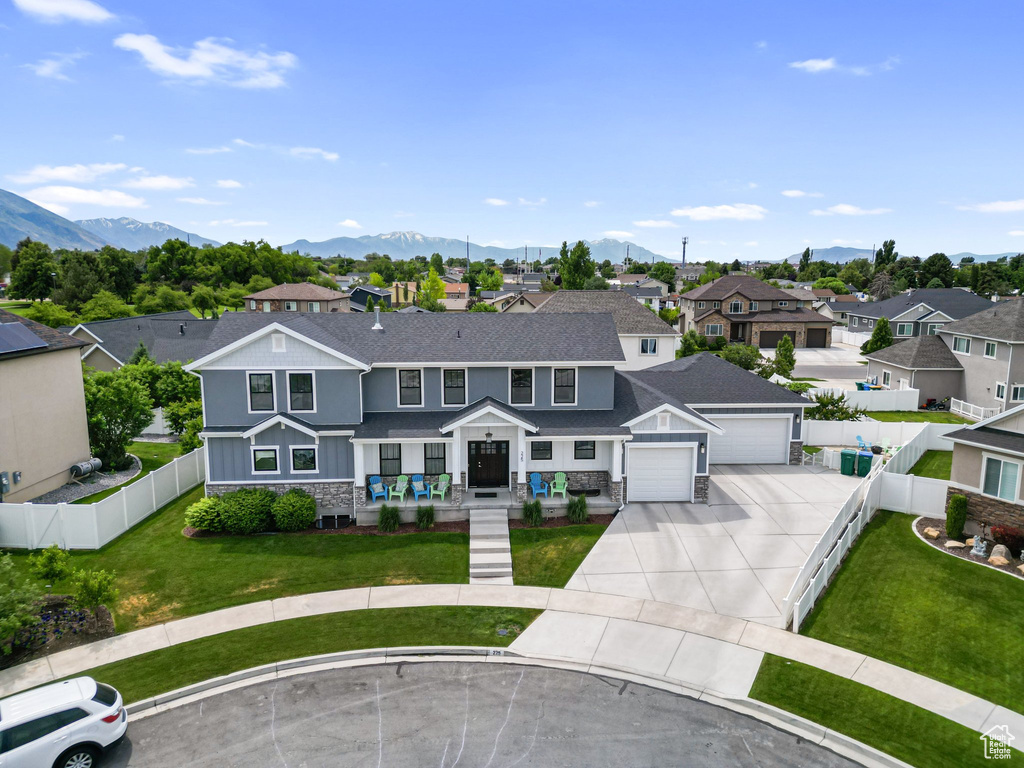 View of front of property featuring driveway, a residential view, stone siding, a mountain view, and board and batten siding