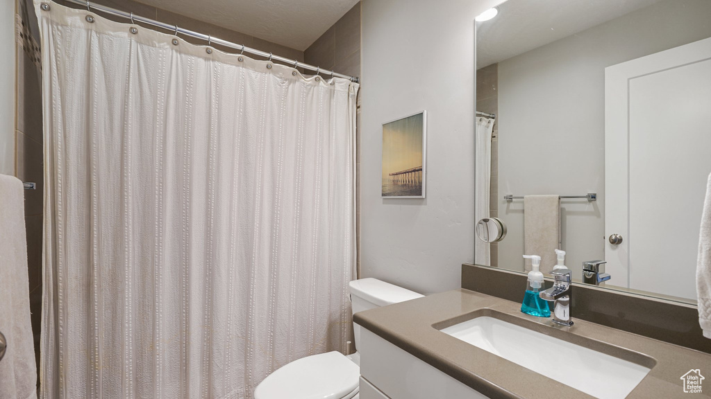 Full bath with toilet, vanity, and a shower with shower curtain