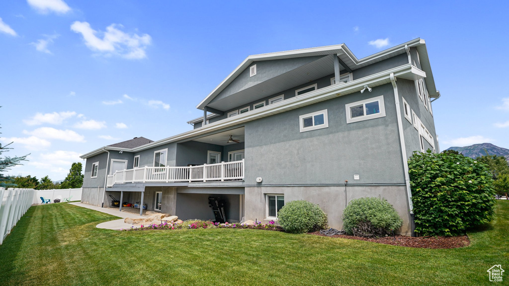 Back of house featuring stucco siding, ceiling fan, and a deck