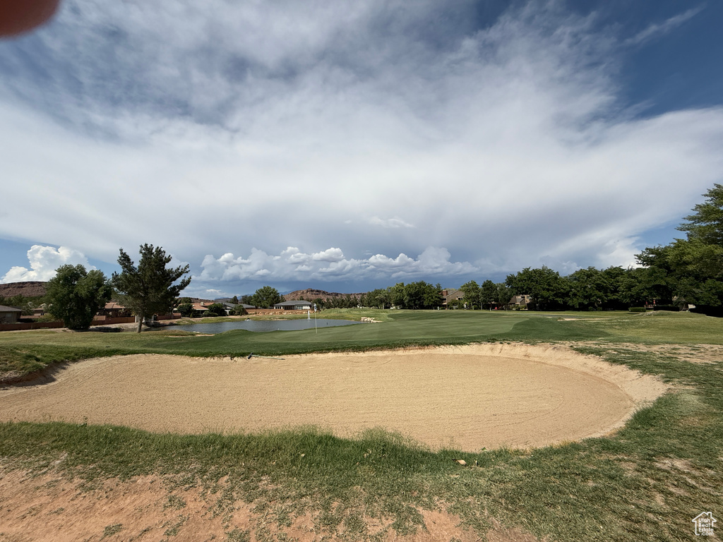 Surrounding community with a water view, golf course view, a putting area, and a lawn