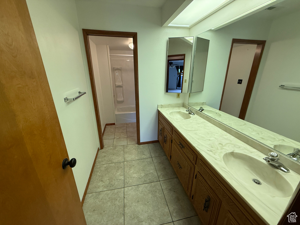 Full bath featuring double vanity, tile patterned flooring, and baseboards