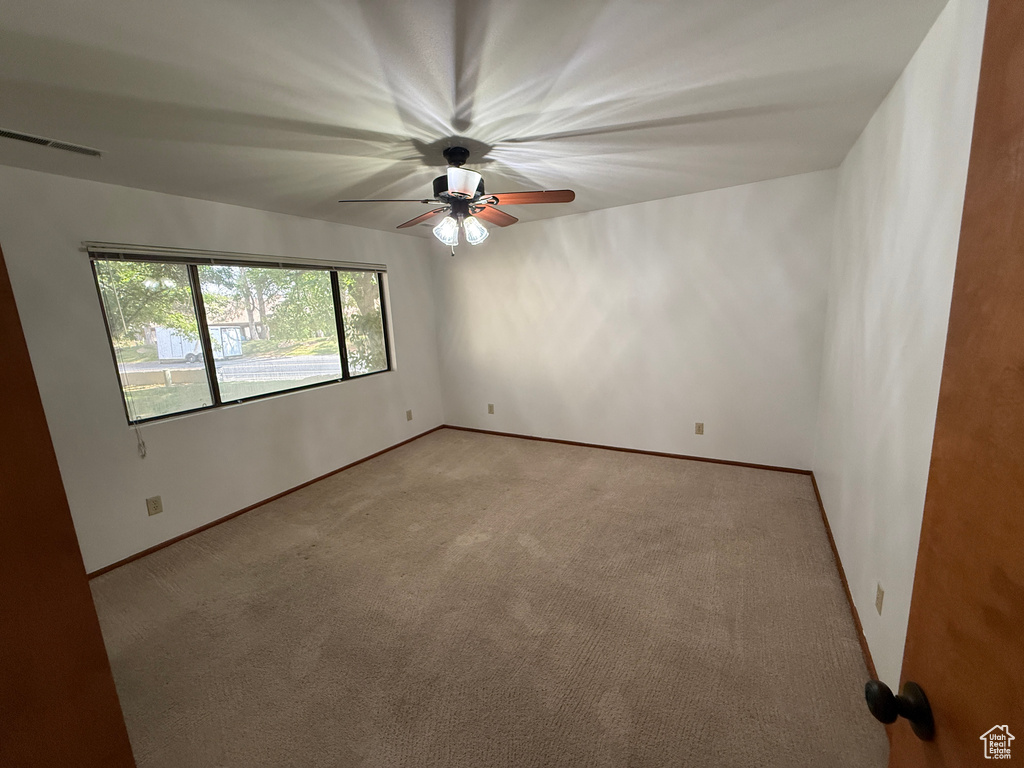 Unfurnished room with a ceiling fan, light colored carpet, and baseboards