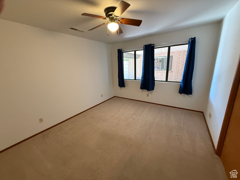 Empty room featuring ceiling fan, light carpet, and baseboards