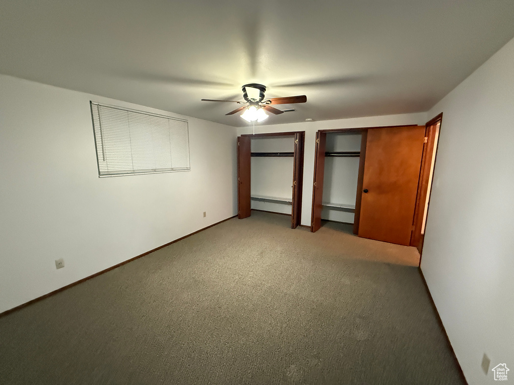 Unfurnished bedroom featuring two closets, light carpet, ceiling fan, and a baseboard radiator