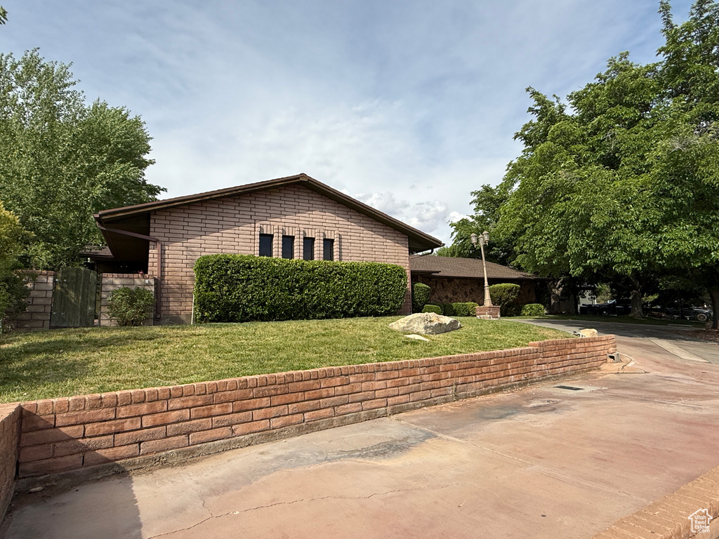 View of side of property with driveway and a lawn