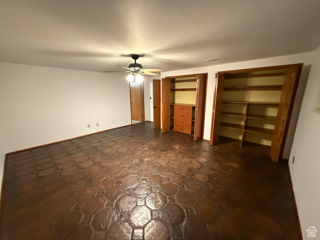 Unfurnished bedroom with two closets and ceiling fan