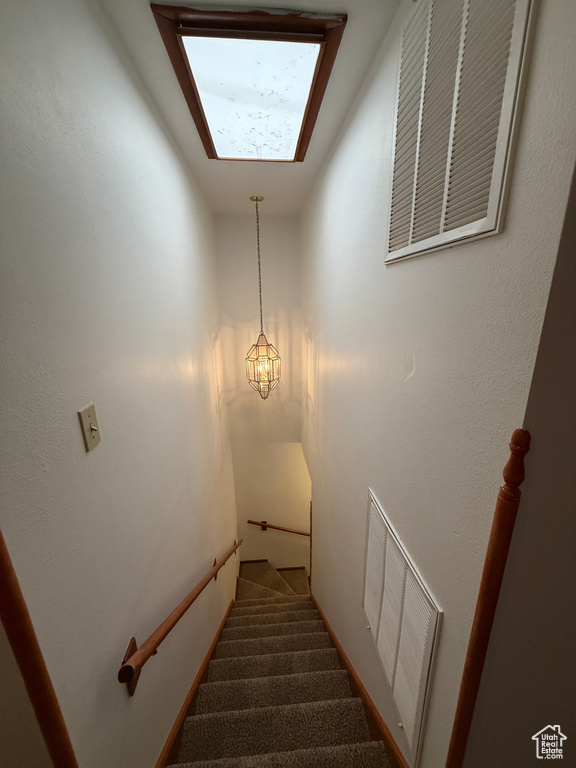 Staircase featuring carpet and a chandelier