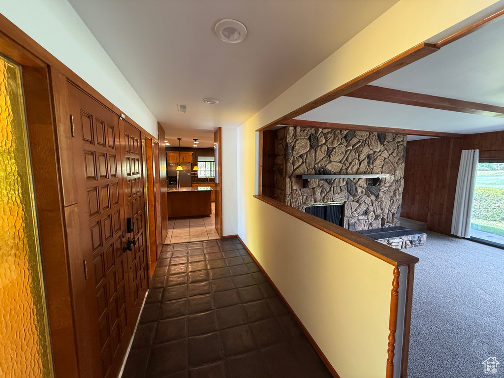 Corridor featuring wooden walls, beam ceiling, and dark tile patterned flooring